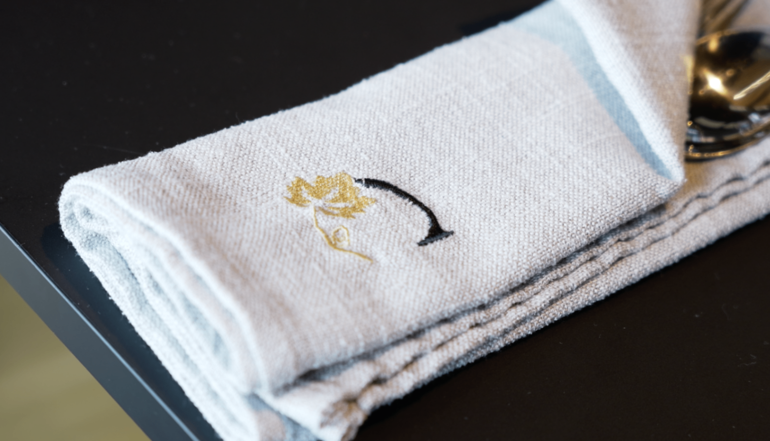 Détail de serviette brodée avec le logo de la maison