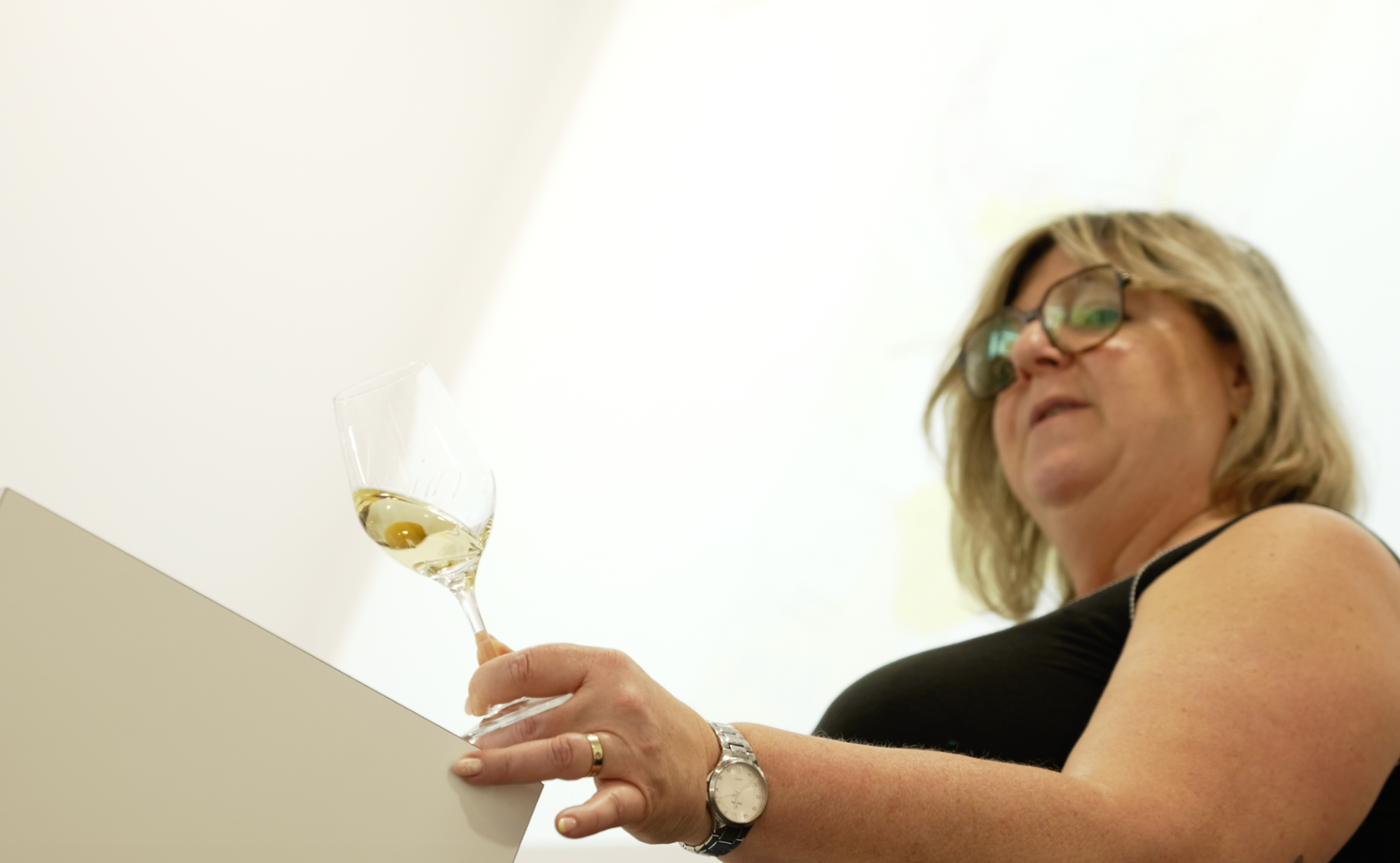 Intervenante tenant un verre de vin blanc en contre-plongée