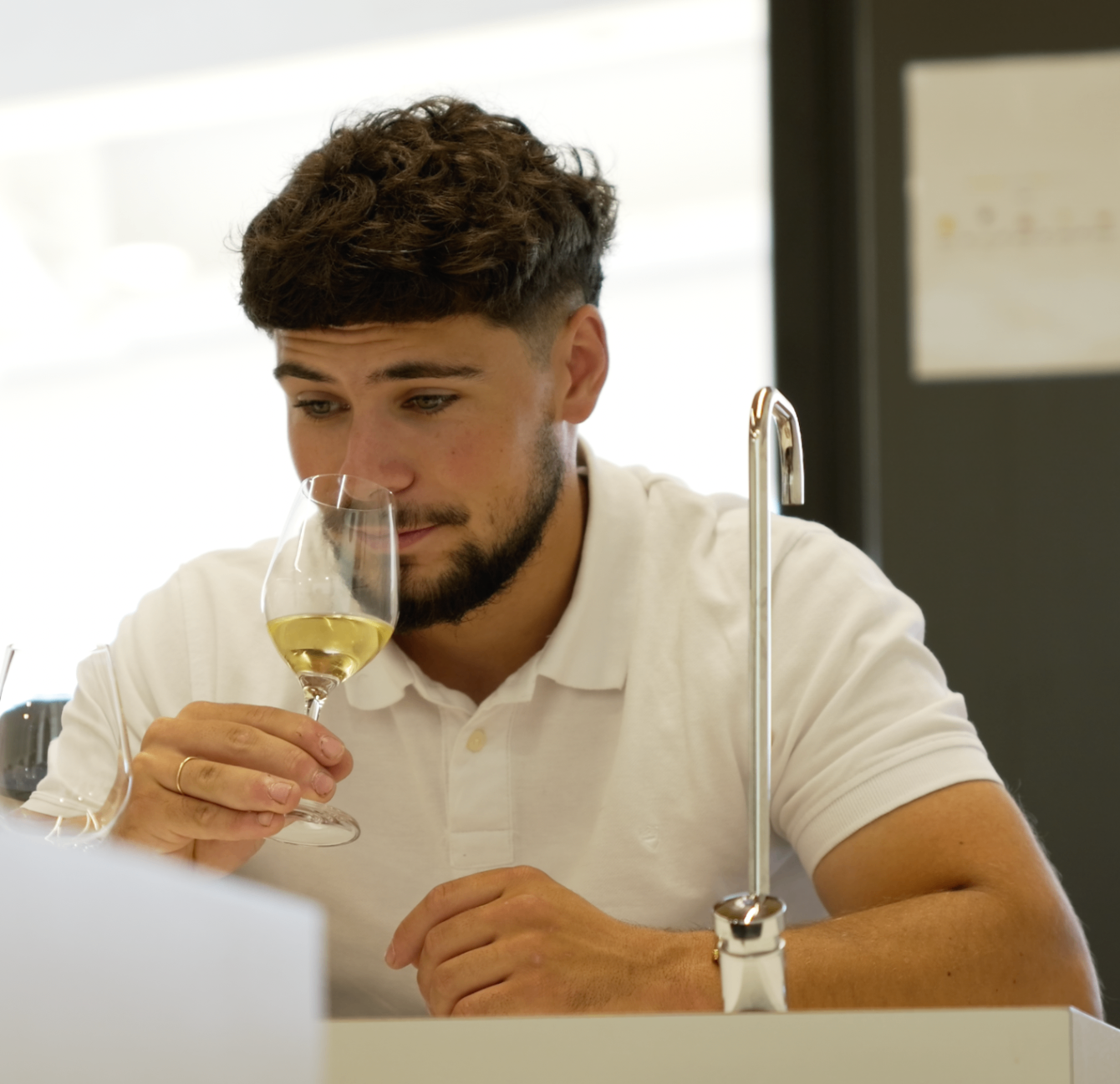 Membre barbu en polo blanc humant un verre de vin blanc