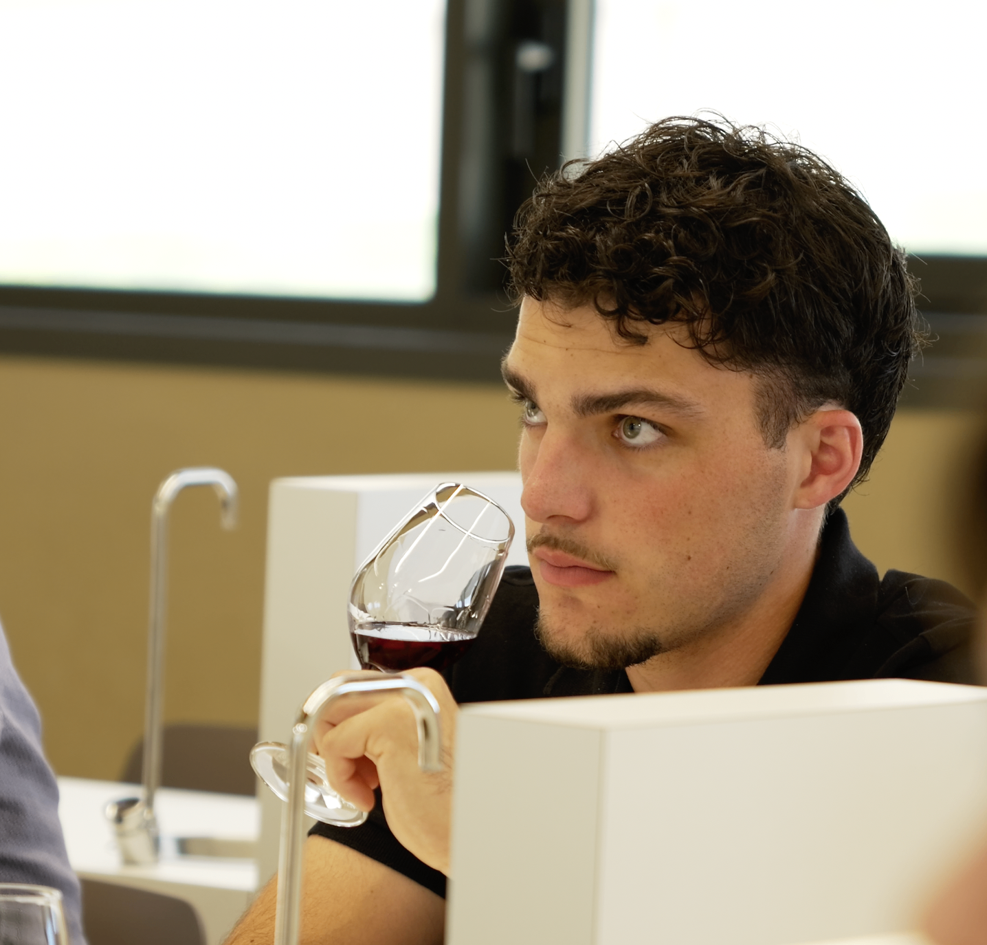 Membre au regard attentif tenant un verre de dégustation