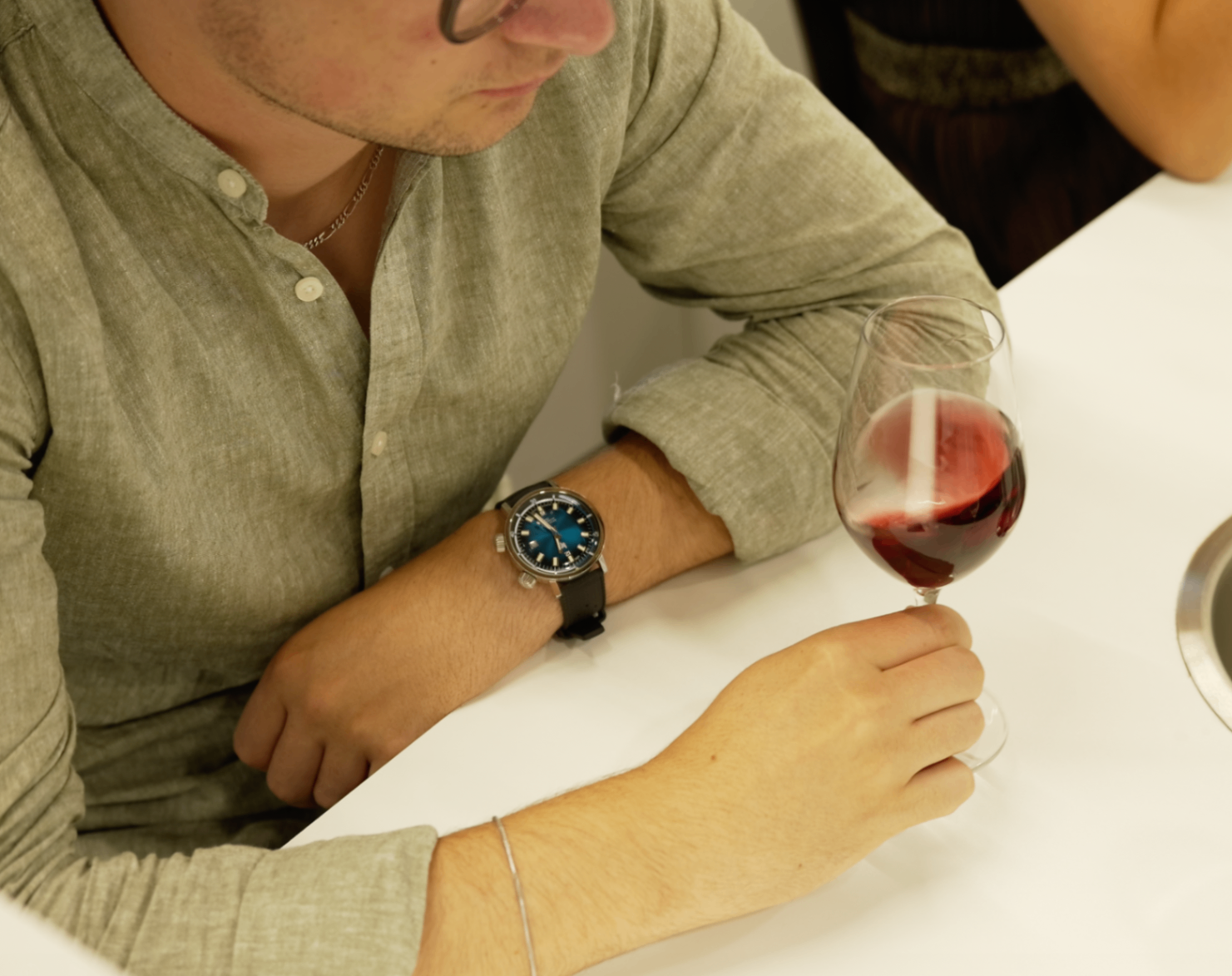 Vue plongeante d'un membre avec montre tenant un verre rouge