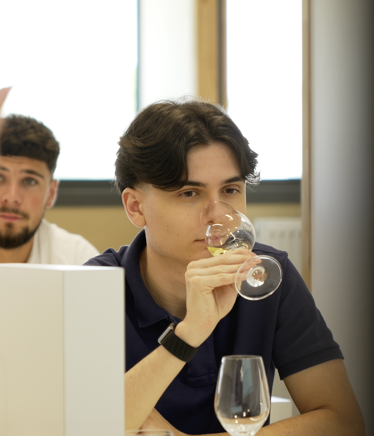 Jeune membre en polo marine humant son verre avec concentration