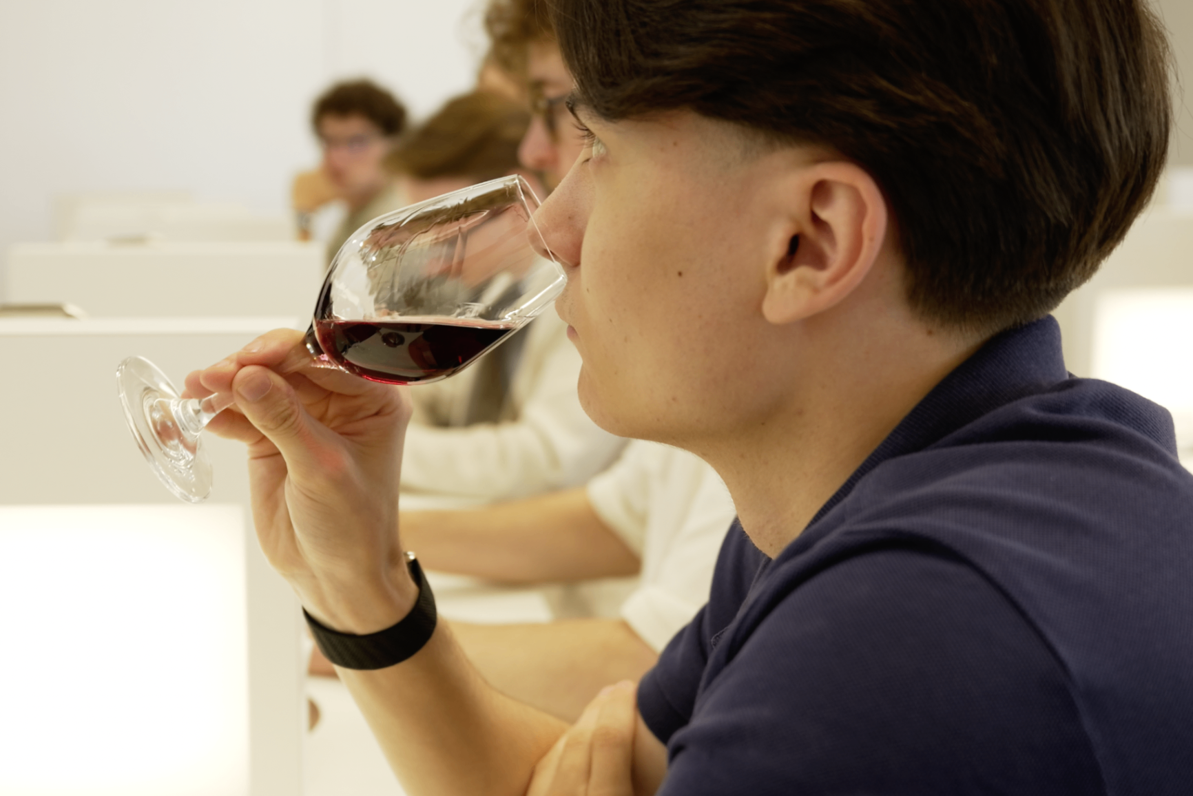 Portrait profil d'un membre en polo bleu dégustant le vin