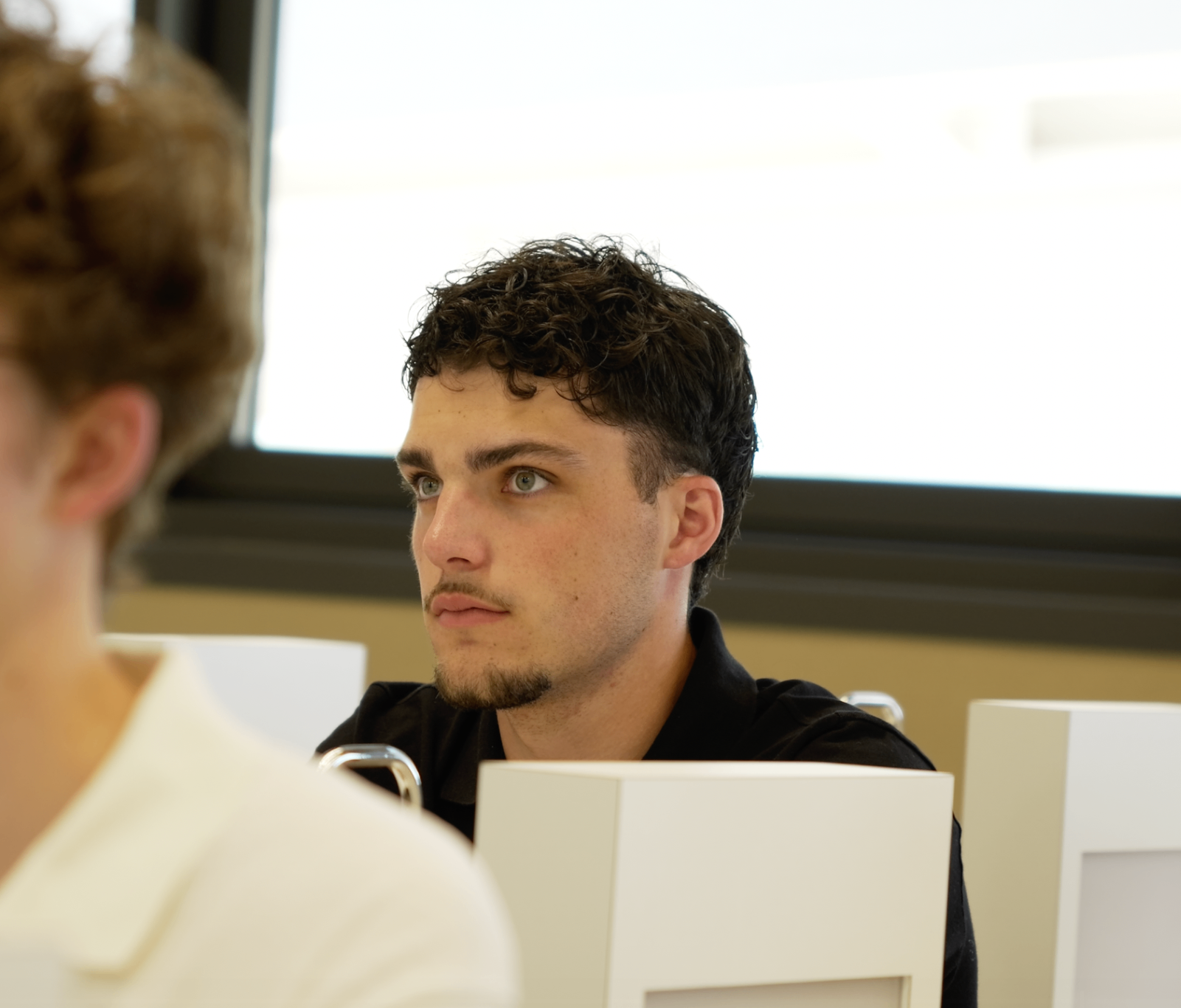 Jeune membre en polo noir concentré pendant la masterclass