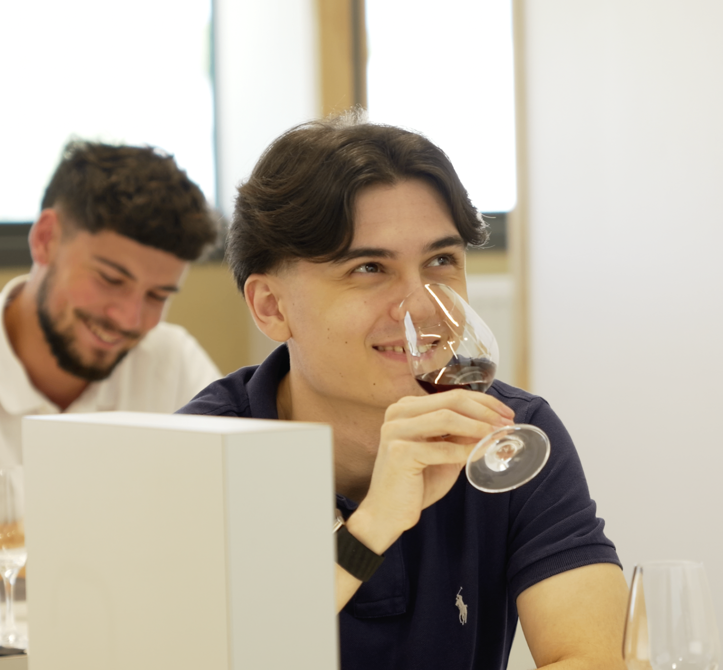Jeune membre en polo marine dégustant un verre avec le sourire