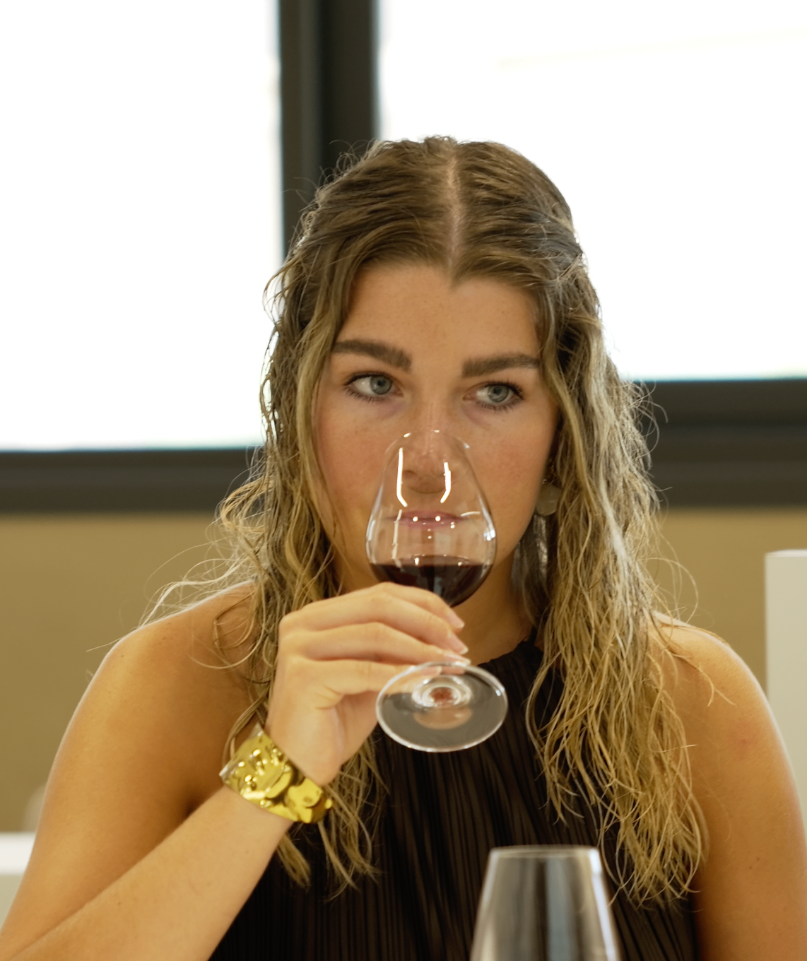 Membre dégustant un vin rouge face caméra